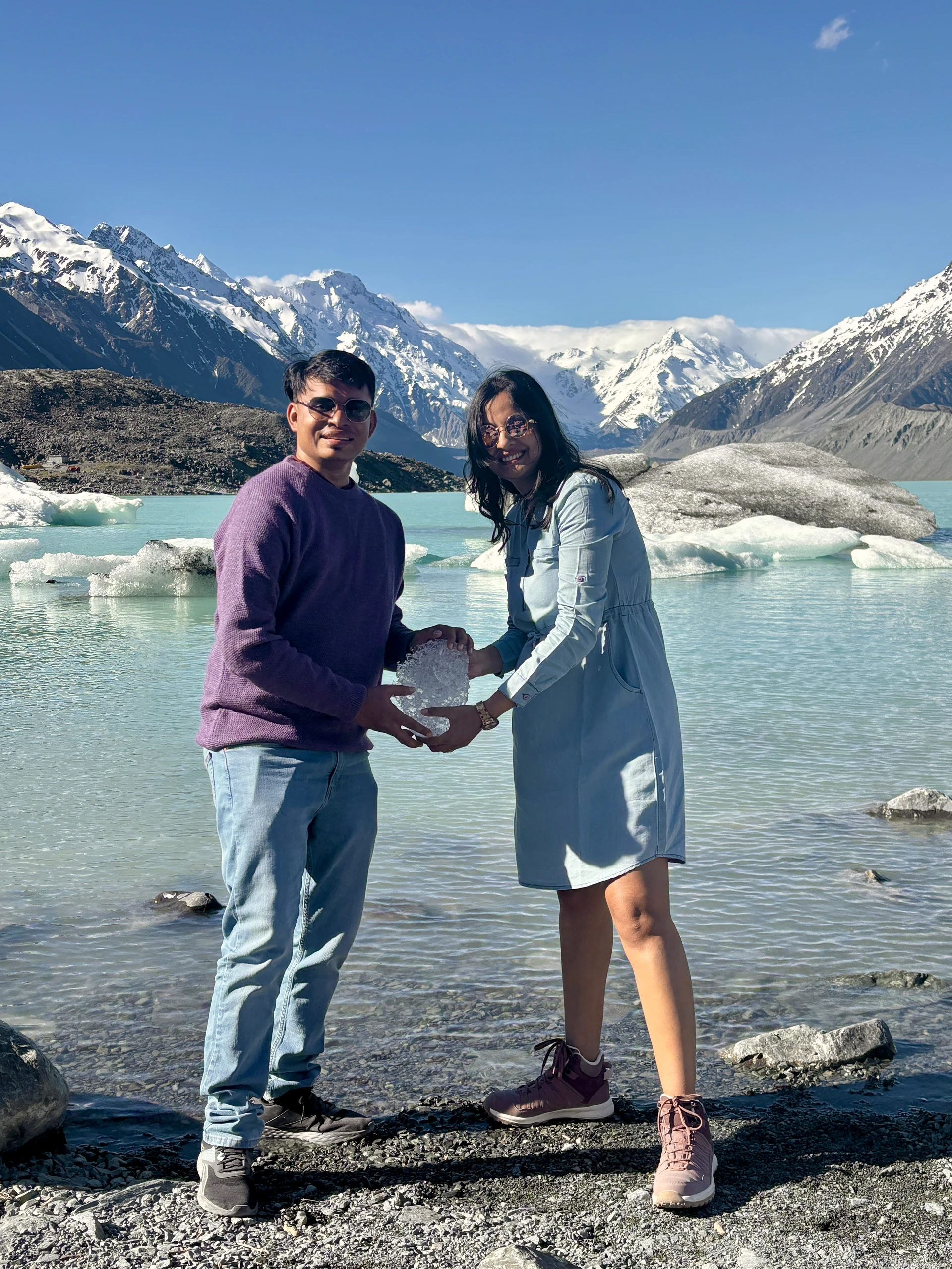 Floating grey icebergs in Tasman Glacier lake below steep rocky moraine
