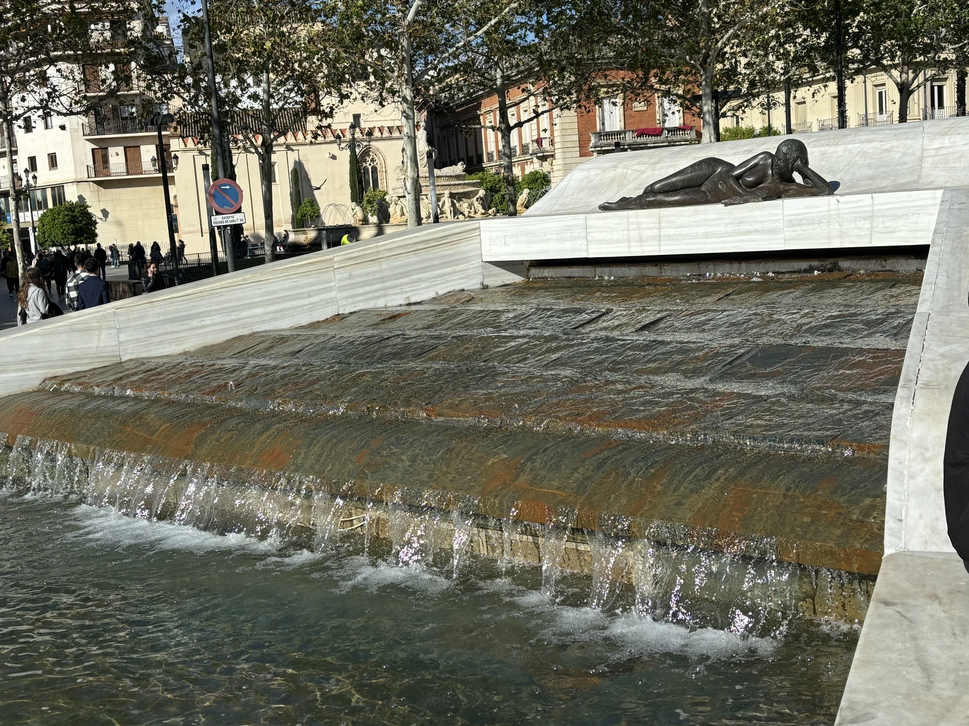 A striking fountain crowned by a bronze sculpture of a reclining woman reading a book in Seville