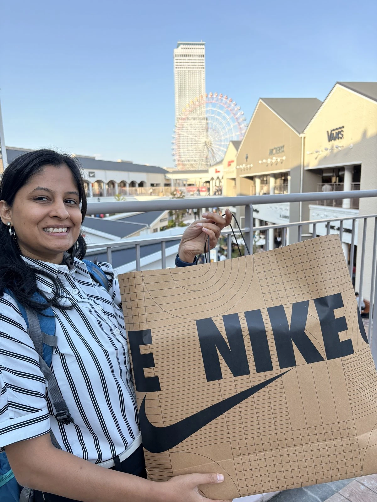 Holding a Nike shopping bag at Rinku Premium Outlet, Ferris wheel in the background