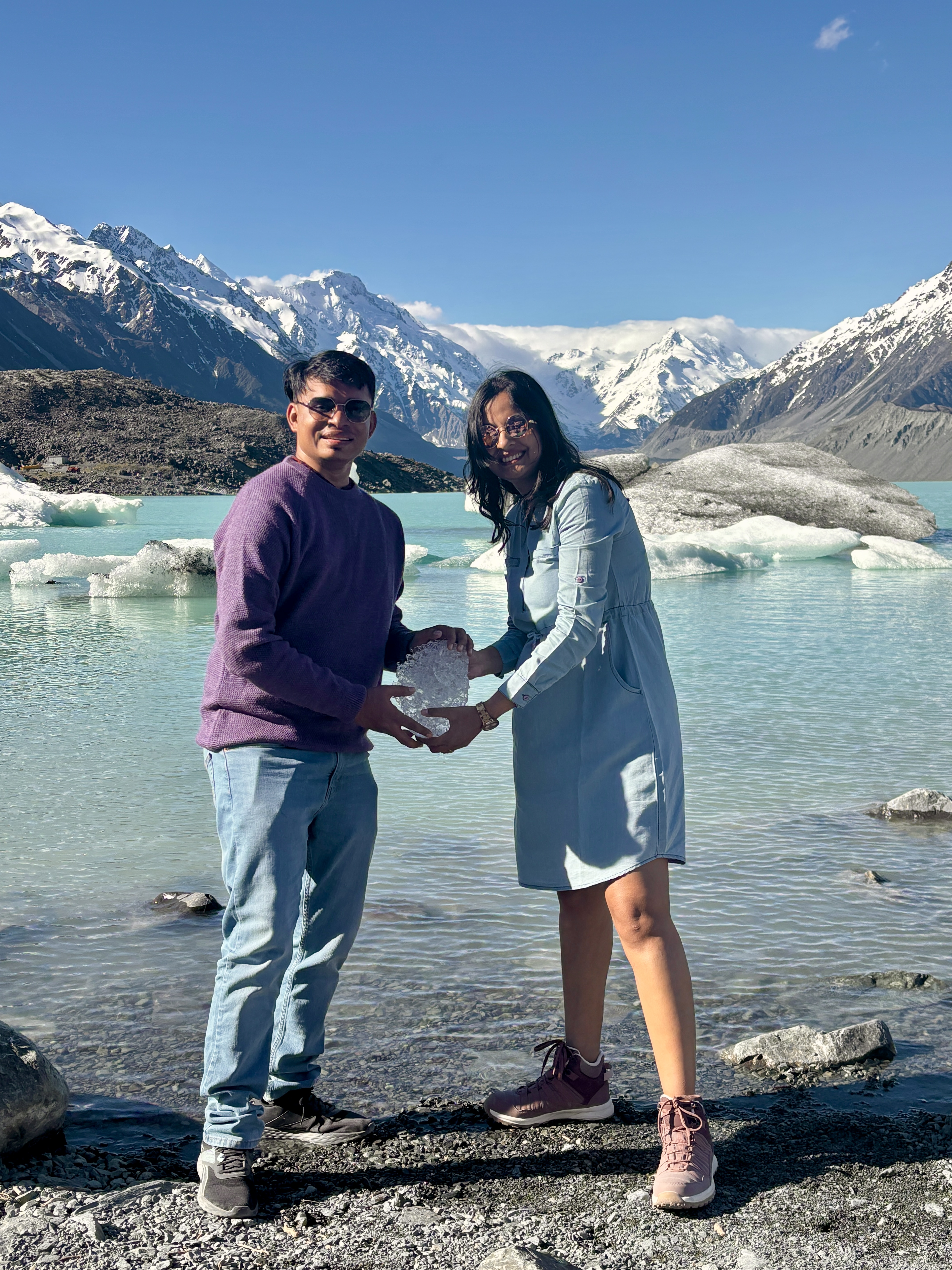 Floating grey icebergs in Tasman Glacier lake below steep rocky moraine