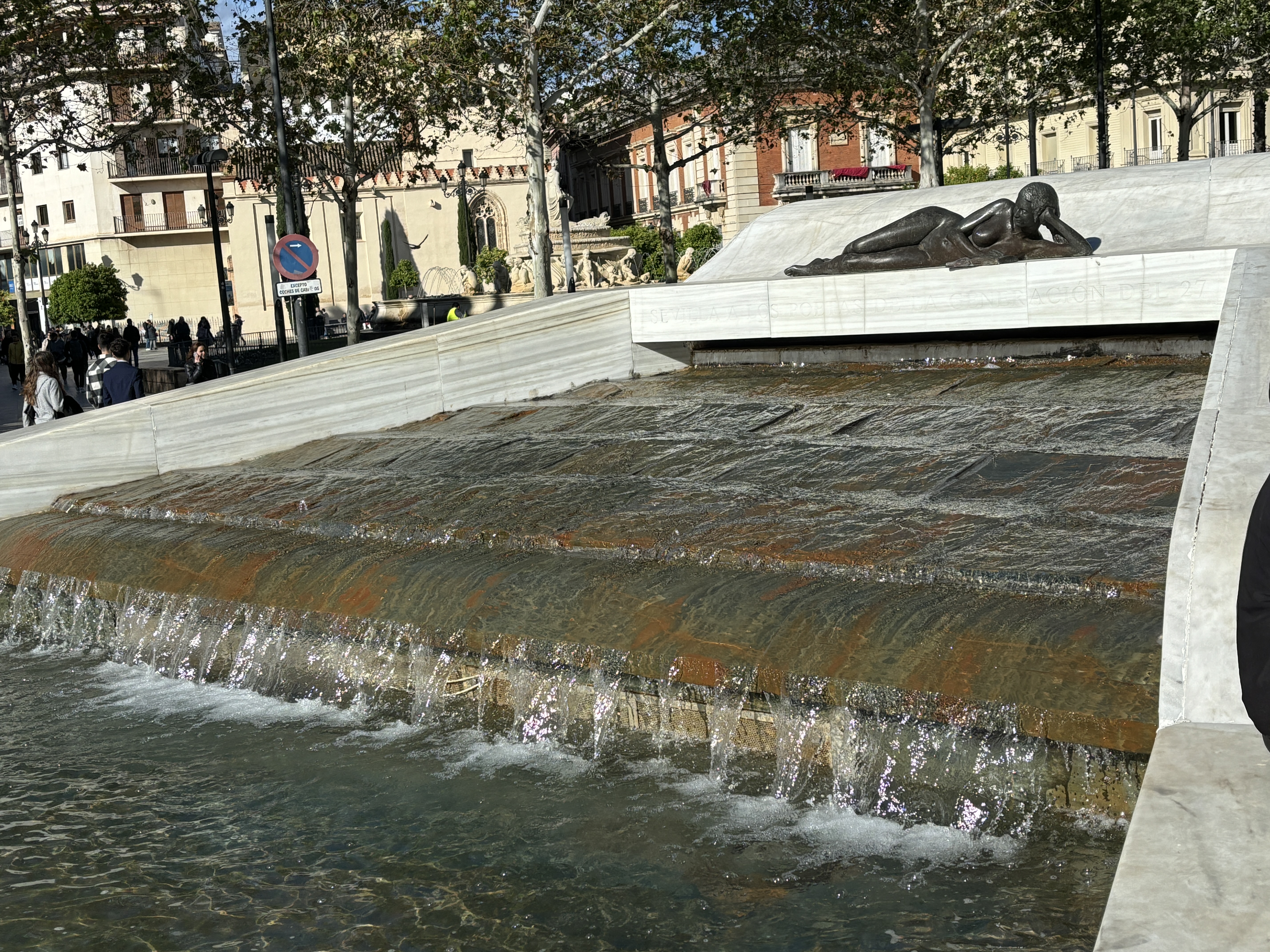 A striking fountain crowned by a bronze sculpture of a reclining woman reading a book in Seville