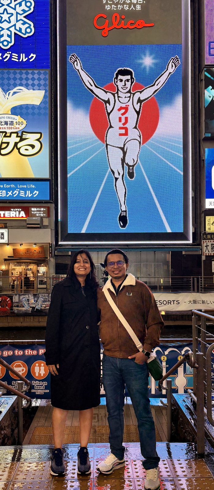 Couple in front of the Glico Running Man billboard in Dotonbori at night